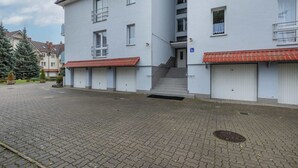 Ein mehrgeschossiges Gebäude mit rotem Ziegeldach, einer Treppe zum Eingang und einem gepflasterten Innenhof.