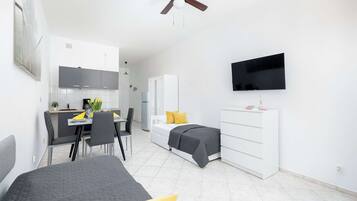 A modern hotel room with a bed, a desk with a chair, a TV mounted on the wall, and a wardrobe.