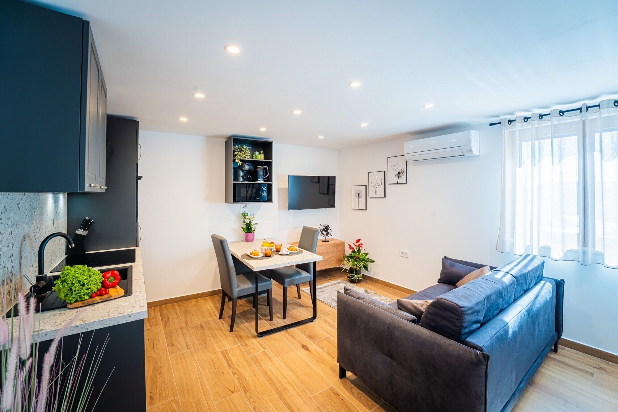 Une cuisine moderne avec un coin repas, un canapé et un téléviseur fixé au mur.
