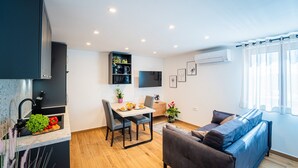 Eine moderne Küche mit Essbereich, einer Couch und einem an der Wand befestigten Fernseher.