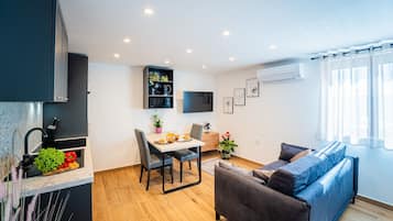 Une cuisine moderne avec un coin repas, un canapé et un téléviseur fixé au mur.