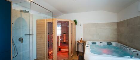 Une salle de bain moderne dotée d’une douche à parois de verre, d’un sauna et d’un jacuzzi.