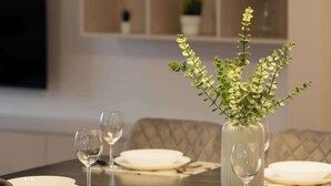 Mesa posta com pratos, copos e um vaso com planta.