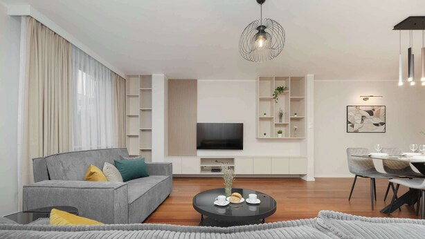 Uma sala de estar moderna com um sofá cinza, uma mesa de centro redonda e uma televisão. Há estantes com plantas e um espaço de jantar com mesa e cadeiras.