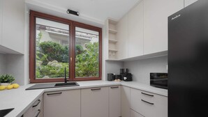 Cozinha moderna com janela, armários brancos e uma geladeira preta.