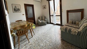 Un espace repas comprenant une table et des chaises, un canapé, un fauteuil à motifs et un lustre.