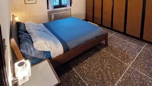 Une chambre à coucher comprenant un lit, une fenêtre, un radiateur, un ventilateur de plafond et une armoire.