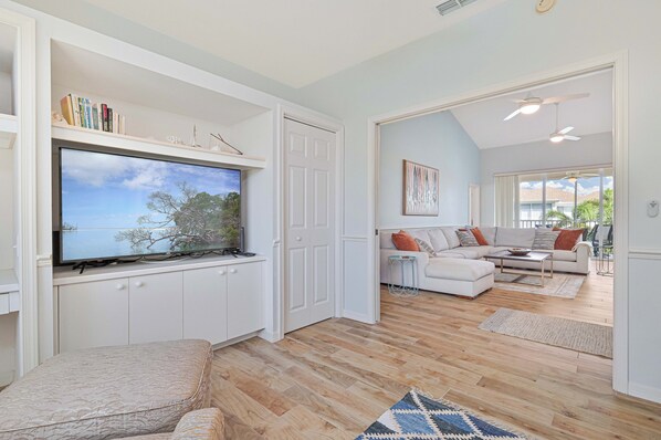 A living room with a flat-screen TV, white cabinets, a sofa, and a coffee table.