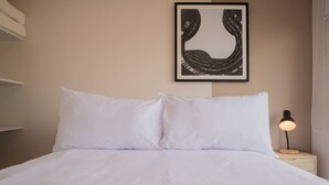 A neatly made bed with white linens, a framed artwork above it, and a bedside table with a lamp. - w Charming 2BR w Balcony in Miraflores (Lima)