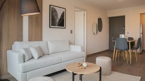 A modern living room with a white sofa, a round wooden coffee table, and a dining area with a table and chairs. - w Charming 2BR w Balcony in Miraflores (Lima)