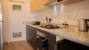 A modern kitchen with wooden cabinets, a granite countertop, stainless steel appliances, and a built-in oven. - w Charming 2BR w Balcony in Miraflores (Lima)