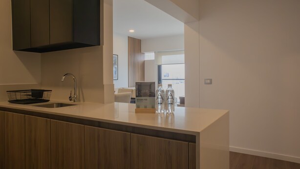 A modern kitchen with a central island, dark cabinets, and a view into the living area. - w Delightful 2BR w Balcony in Miraflores (Lima)