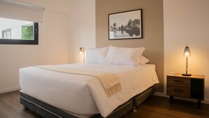 A neatly made bed with a quilted mattress, a bedside table with a lamp, and a framed picture on the wall. - w Delightful 2BR w Balcony in Miraflores (Lima)