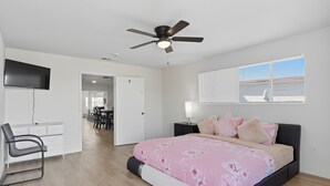 A modern bedroom with a bed, a desk, a chair, and a ceiling fan. - Relaxing Paradise Hills Retreat 4 Bedroom Home (San Diego)