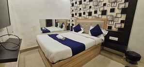 Habitació d'hotel amb un llit, un mirall, una paret amb un dibuix geomètric i un petit gresol.