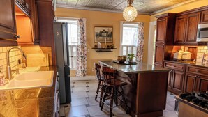 Una cocina con una isla central, taburetes de bar, un refrigerador de acero inoxidable y armarios de madera.
