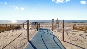 A wooden boardwalk leading to a beach with a clear sky.