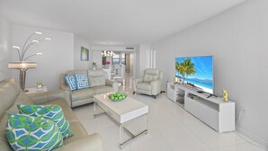 Een moderne woonkamer met een bank, fauteuils, een salontafel en een televisie.