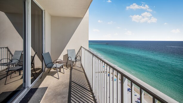 A balcony with chairs and a view of the ocean.