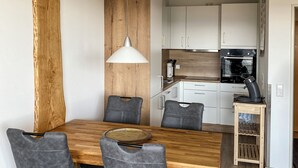 A modern kitchen with white cabinets, a wooden dining table, and grey upholstered chairs.