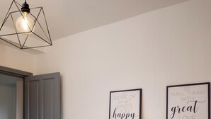 Ein Schlafzimmer mit einem Bett, zwei Wandbildern, einer Hängeleuchte und einer Tür.
