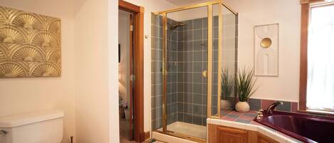 A bathroom with a toilet, a shower with a glass door, a bathtub, and a sink with a mirror.