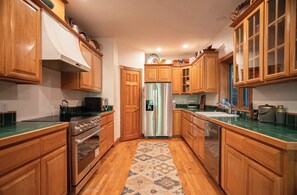 Eine Küche mit Holzschränken, einem Edelstahlkühlschrank und einem gemusterten Teppich.