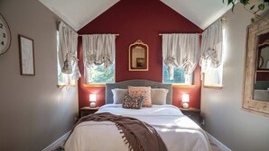 Une chambre à coucher avec un lit, deux tables de chevet avec des lampes, un miroir et des rideaux.