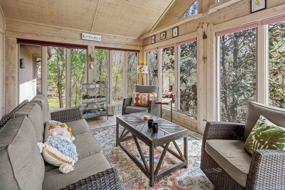 A sunroom with a sofa, a coffee table, and a wicker chair.