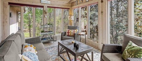 A sunroom with a sofa, a coffee table, and a wicker chair.