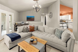 A modern living room with a sectional sofa, a wooden coffee table, and a chandelier. - Bella Vista Retreat sleeps 8 | Game Room + Trails (Bella Vista)