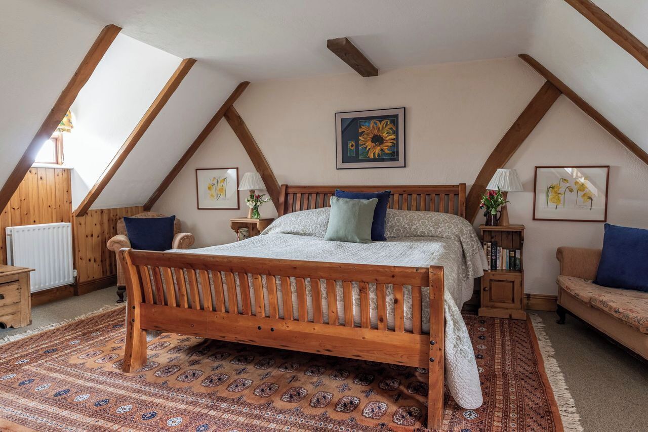 Ein Schlafzimmer mit einem hölzernen Bett, einem gemusterten Teppich und Holzbalken an der Decke.