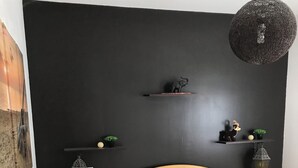 A bedroom with a wooden bed, white bedding, a dark wall, and a hanging light fixture. - Contemporary, single-storey house (Corme-Royal)