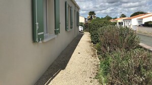 A building with a gravel path leading to a white car parked on the street. - Contemporary, single-storey house (Corme-Royal)