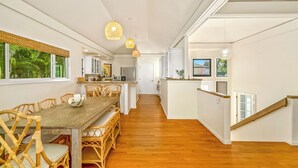 Una cocina moderna con una mesa y sillas de madera, una escalera y vistas al exterior.
