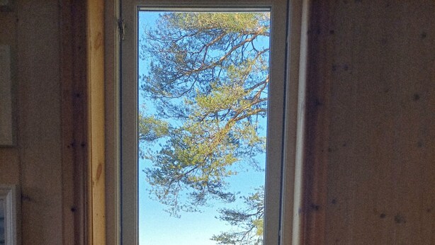 L’intérieur d’un chalet en bois, avec vue sur un lac à travers une porte vitrée.