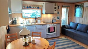 Une pièce confortable, aménagée dans le style d’un chalet, avec une table à manger en bois, des chaises, un canapé et un coin cuisine équipé d’une cuisinière, d’un évier et de placards.