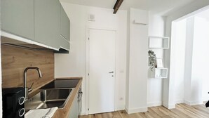 A modern kitchen with a wooden countertop, stainless steel sink, and white cabinets.