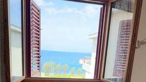 A bedroom with a view of the sea through a window with wooden shutters. - Sailor's House (Milazzo)
