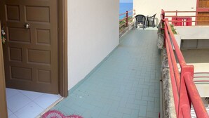 A corridor with a tiled floor leading to a balcony with a view of the sea. - Sailor's House (Milazzo)