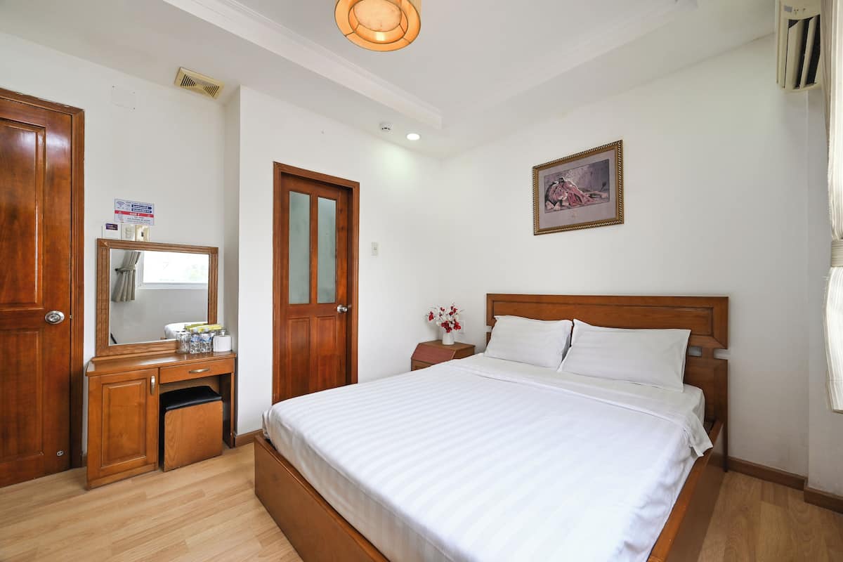 Une chambre à coucher avec un lit en bois, une table de chevet, une commode, un miroir et un tableau encadré accroché au mur.