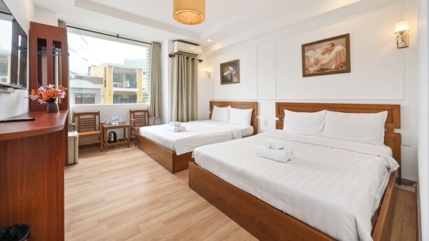 Een hotelkamer met twee bedden, een bureau, een stoel, een klein tafeltje en een raam met gordijnen.