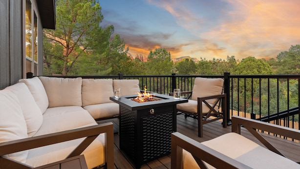 A deck with a sofa, chairs, and a fire pit.