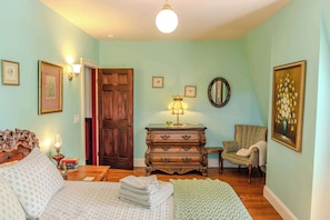 Une pièce comprenant un lit, une commode, une chaise et une porte.