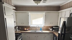 A kitchen with white cabinets, a stainless steel refrigerator, a microwave, and a stove. - 3-bedroom house near Texas Tech University (Lubbock)