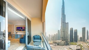 Une chambre d’hôtel moderne avec balcon, télévision et vue sur la ville, notamment sur le Burj Khalifa.