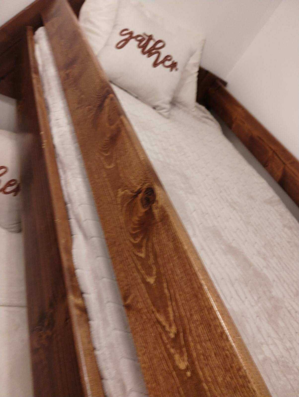 Ein Bettgestell aus Holz mit einer weißen Matratze und einem Kopfkissen mit dem Schriftzug 'gather'.