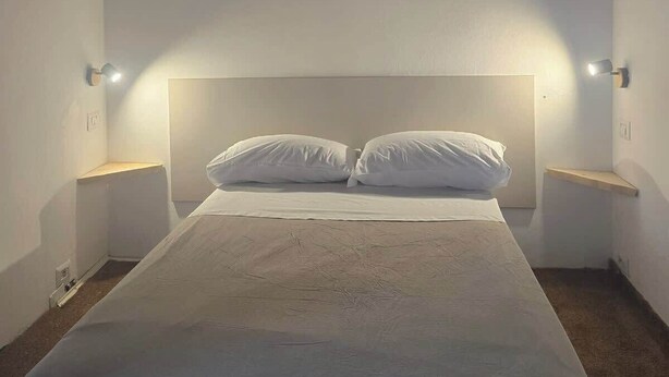 A bedroom with a large bed, two bedside tables, and a wooden ceiling. - Steps to Duomo: Historic Florence Studio (Florence)