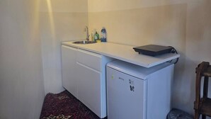 A compact kitchen with a sink, a small refrigerator, and a countertop with a laptop. - Steps to Duomo: Historic Florence Studio (Florence)