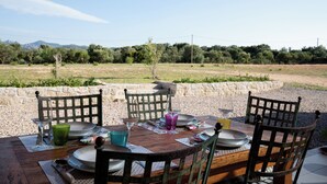 An outdoor dining area with a table set for four, surrounded by chairs, and a scenic view of trees and mountains in the background.